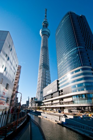 東京スカイツリーと川沿いの高層ビルが青空に染まる綺麗な写真素材