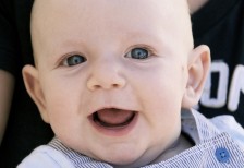 透き通ったブルーの目が綺麗な笑顔の赤ちゃんの写真素材
