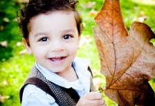 落ち葉を拾って笑顔の少年の写真。コントラストの強い鮮やかな色合い。