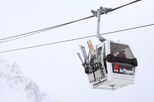 スキー用のゴンドラに乗る人を撮影した写真素材。一面真っ白に染まったゲレンデがキレイ。