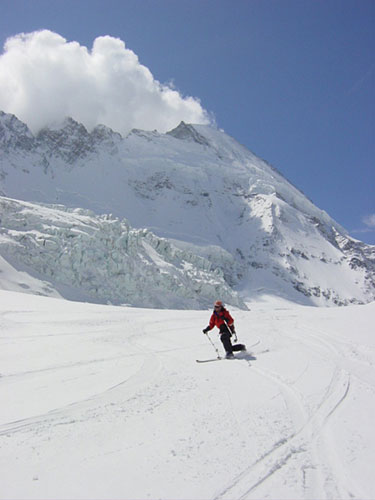 スキーをする人物の写真素材。背景のゲレンデと雪山大きく切り取った迫力のある構図