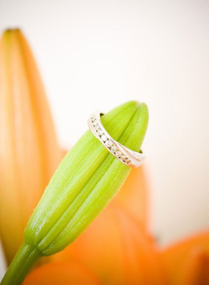 結婚式の指輪の写真素材。背景の花びらのオレンジと緑のつぼみが綺麗