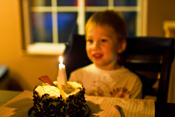 火のついたキャンドルがのったバースデーケーキを目の前にした男の子の写真素材