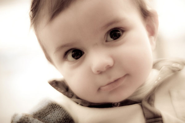 クリっとした目がキュートな赤ちゃんの写真。セピア調のレトロな雰囲気