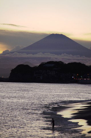 海岸と富士山を撮影した写真素材。小さく入った人物がスケール感を際立てた一枚。