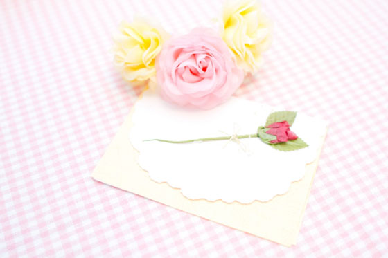 手紙と花の飾りを撮影した写真素材。ピンクと黄色の色合いが可愛い雰囲気。